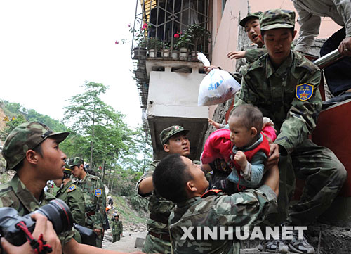 5月13日，在震后的北川縣城，武警戰(zhàn)士將一名和家人失散的幼童救出。 記者從四川省綿陽市抗震救災指揮部了解到，受災特別嚴重的北川縣老縣城80%、新縣城60%以上的建筑物因地震垮塌，縣城周邊發(fā)生大面積山體滑坡。