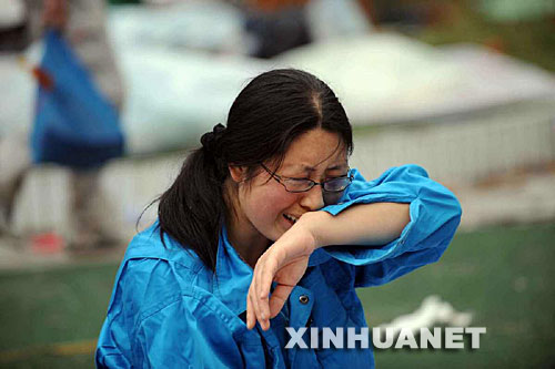 5月14日，張關(guān)蓉在丈夫譚千秋的遺體旁痛哭。 受汶川地震影響，四川省德陽市東汽中學(xué)教學(xué)樓坍塌。在地震發(fā)生的一瞬間，該校教導(dǎo)主任譚千秋雙臂張開趴在課桌上，身下死死地護(hù)著4個(gè)學(xué)生，4個(gè)學(xué)生都獲救了，譚老師卻不幸遇難。 新華社記者王建華攝 