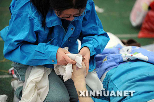 5月14日，張關(guān)蓉在擦拭丈夫譚千秋的遺體。 受汶川地震影響，四川省德陽市東汽中學(xué)教學(xué)樓坍塌。在地震發(fā)生的一瞬間，該校教導(dǎo)主任譚千秋雙臂張開趴在課桌上，身下死死地護(hù)著4個(gè)學(xué)生，4個(gè)學(xué)生都獲救了，譚老師卻不幸遇難。 新華社記者王建華攝