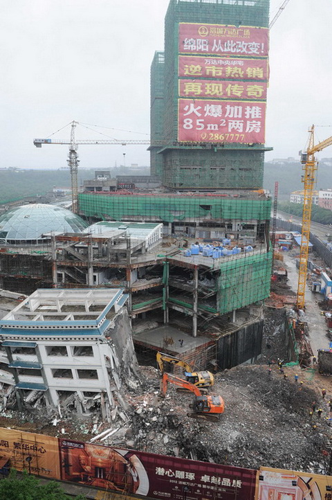 5月21日，工程機械在拆除綿陽紫荊民族中學(xué)校舍，旁邊則是建設(shè)中的萬達廣場。