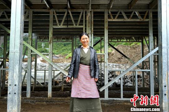 西藏隆子縣玉麥鄉(xiāng)位于中印邊境，是中國人口最少的行政鄉(xiāng)，全鄉(xiāng)56戶農(nóng)牧民將于今年搬遷至新房。圖為7月14日，玉麥鄉(xiāng)群宗站在框架已經(jīng)搭建好的新房門前，喜笑顏開?！〗w波 攝