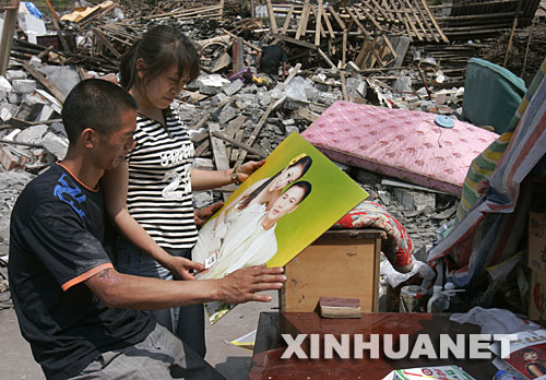 5月19日，雖然相框損壞了，夫妻倆還是仔細地把結婚照擦拭干凈。 四川省什邡市鎣華鎮(zhèn)仁和村三組的梁正彬一家很幸運，大地震發(fā)生時，包括老父母和年幼女兒在內的全家5口人都跑出了轟然倒塌的房屋。“平安就是福！”他們默默收拾廢墟中的家，準備重建家園。