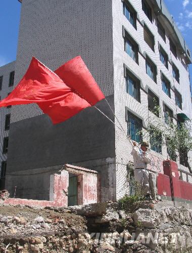  7月5日，一名防化兵高舉紅旗在北川縣城內(nèi)行走。當(dāng)日，記者經(jīng)特許進(jìn)入地震重災(zāi)區(qū)北川縣城采訪，用相機(jī)記錄下北川縣城的現(xiàn)狀。 